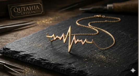 Bespoke Qutahia Jewelry 14K and 9K solid yellow and rose gold heartbeat necklace with integrated heart resting on textured dark Turkish slate in a traditional Kütahya artisan workshop environment.