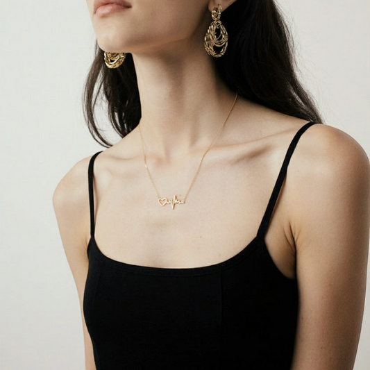 Woman wearing a gold necklace with a heart design on a plain background
