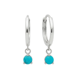 Qutahia Jewelry 14k solid gold huggie earrings with dangling turquoise gemstones in a claw setting.